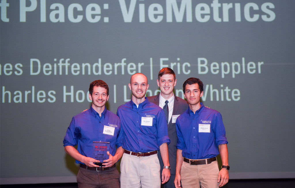 First place winners, VieMetrics smiling on stage with trophy
