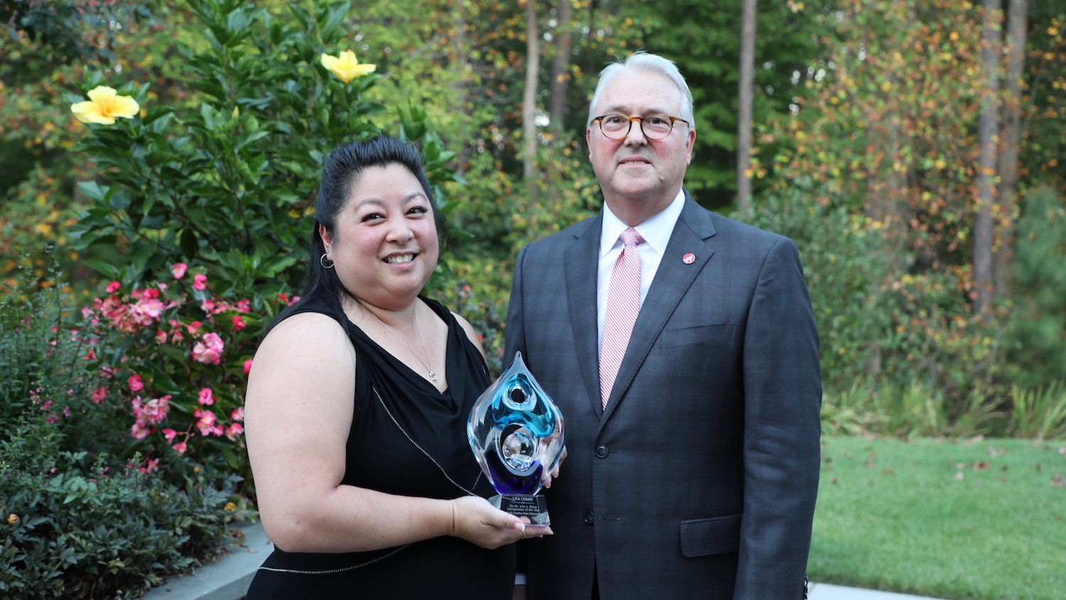 Lisa Chang smiling next to Chancellor Randy Woodson while holding her Risley award.