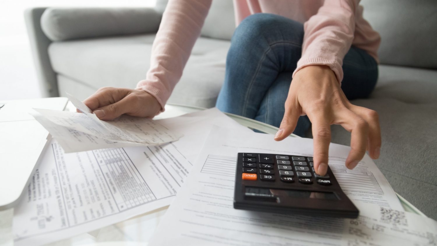 Pile of paper bills while woman calculates payment on calculator
