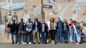 Albright Entrepreneurs Village students pose with wolf signs by the mural in downtown Cary.