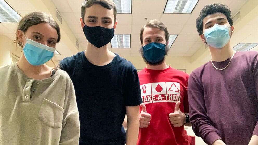 Four students wearing masks celebrate their make a thon 2021 victory