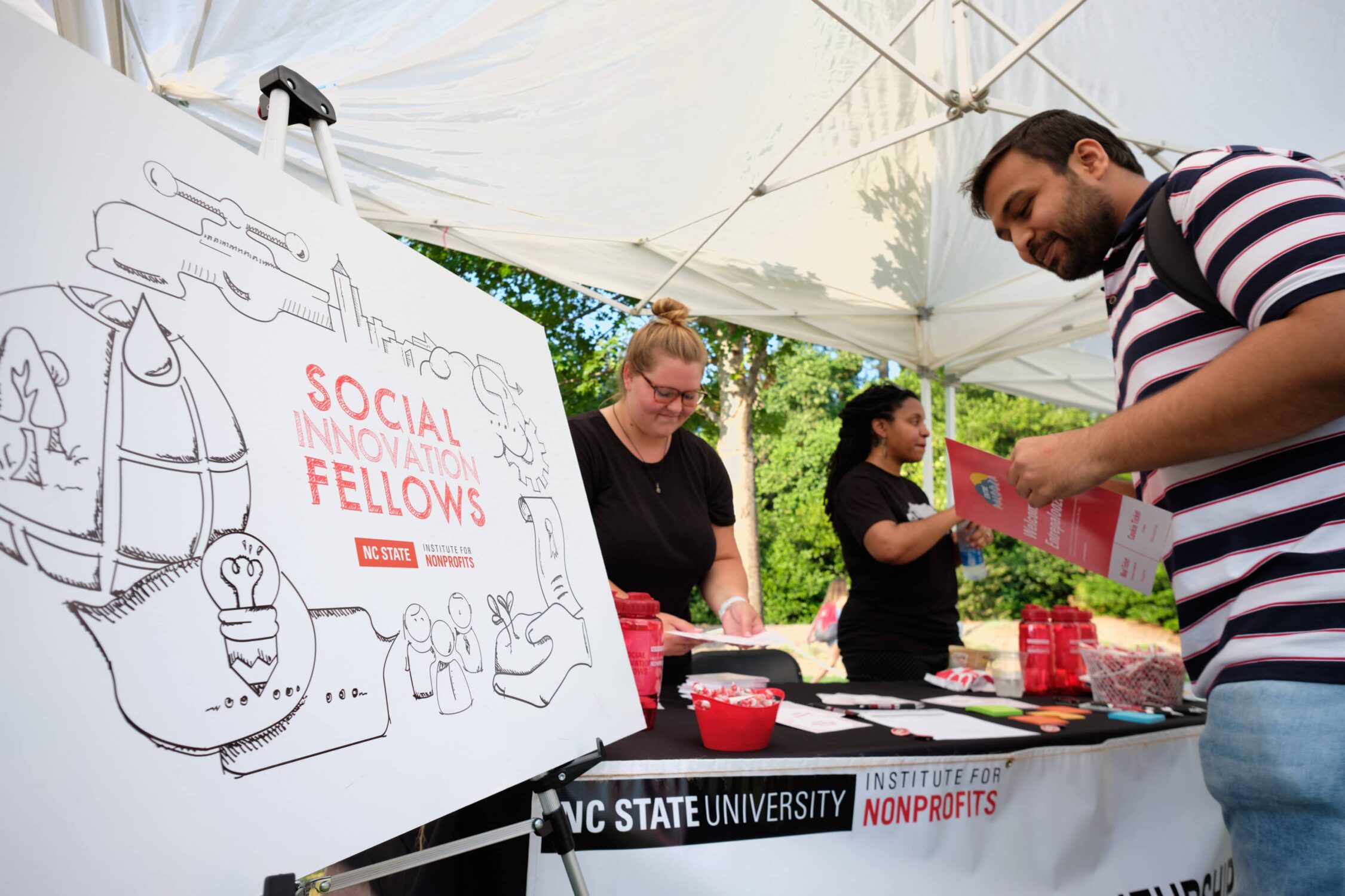 man reading flyer while at the social innovation fellows booth