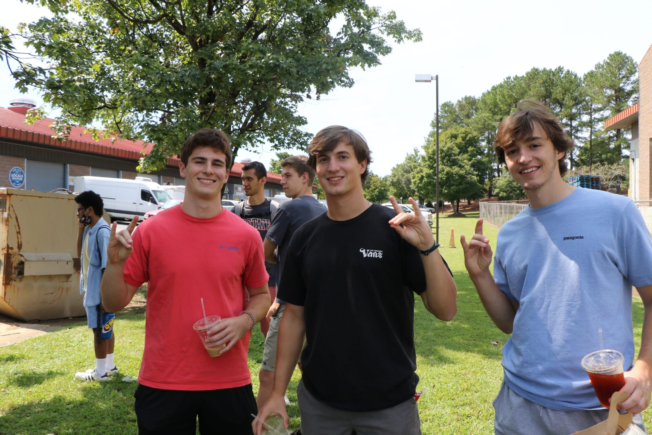 State students holding wolfpack signs while holding 321 iced coffee