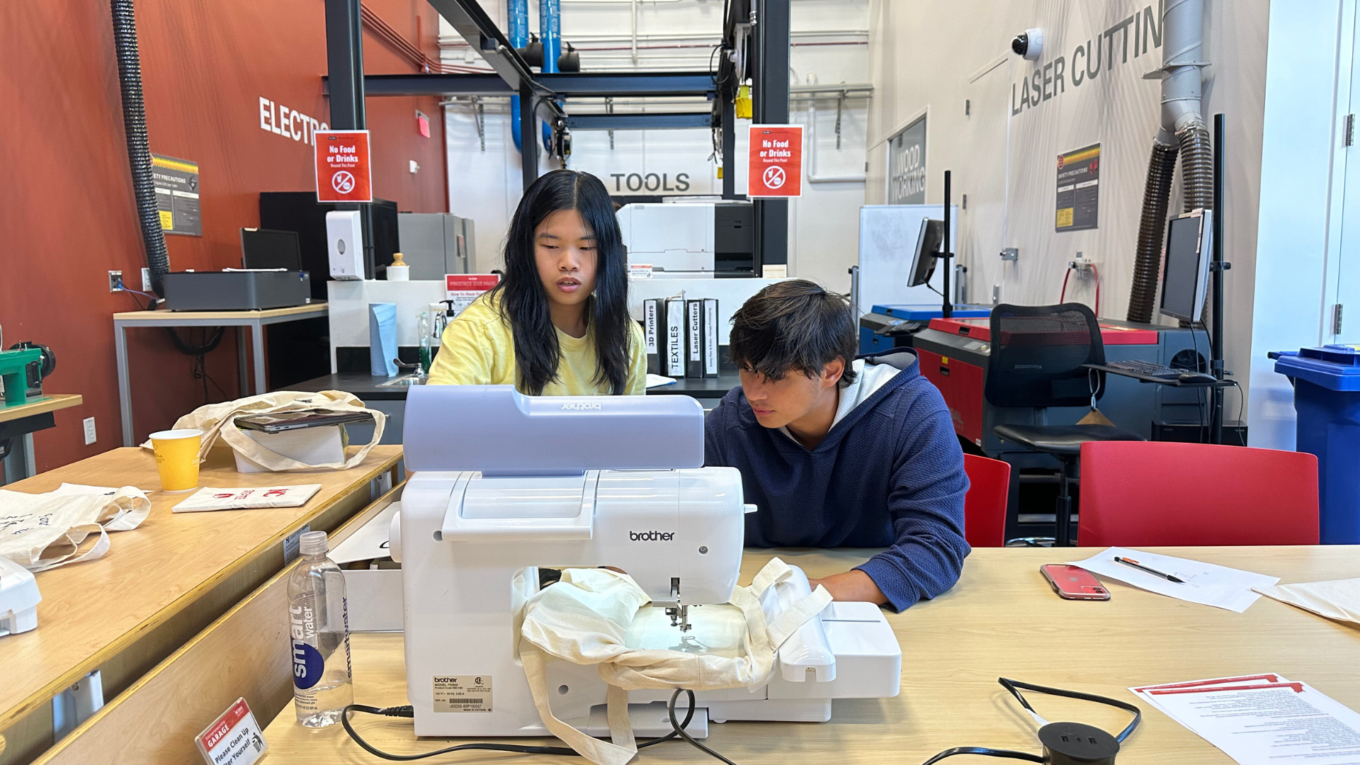 Two students working on an embroidery machine