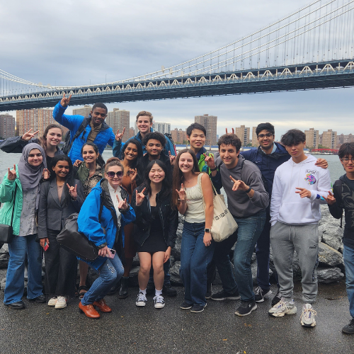 Group of people posing in front of a bridge.